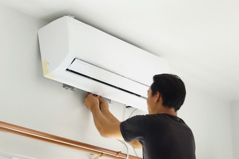 Image of someone setting up a ductless system. Video - Choose a Ductless System for Your Home Remodel.