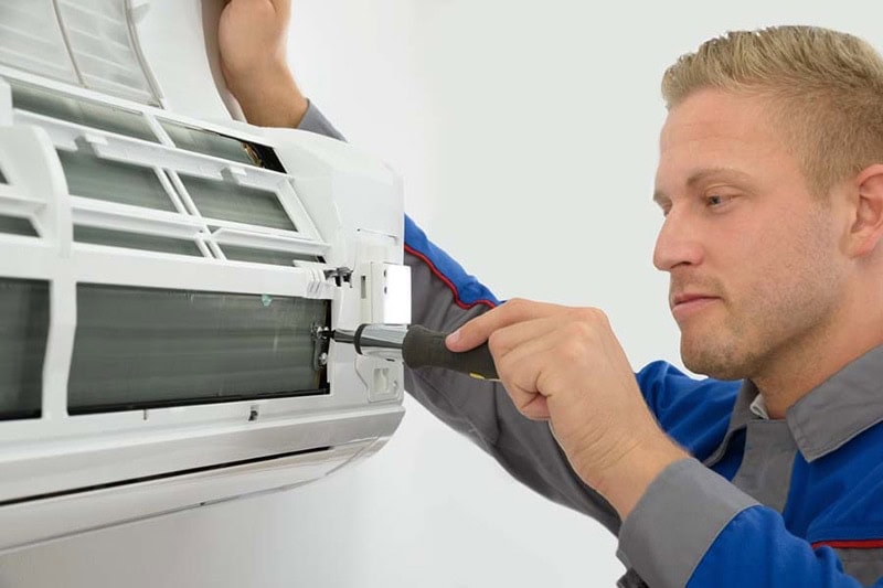 Do I Really Need an AC Tune-Up? Portrait Of Young Male Technician Repairing Air Conditioner