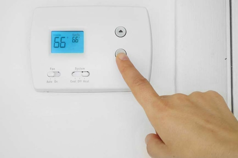 A hand lowering the temperature on a thermostat | Is It Normal for My AC to Turn On and Off? | Fort Collins