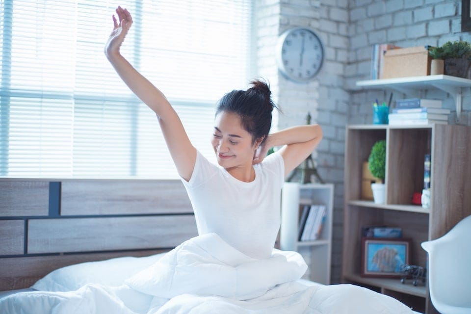 Woman waking up after sleeping well with AC on in home