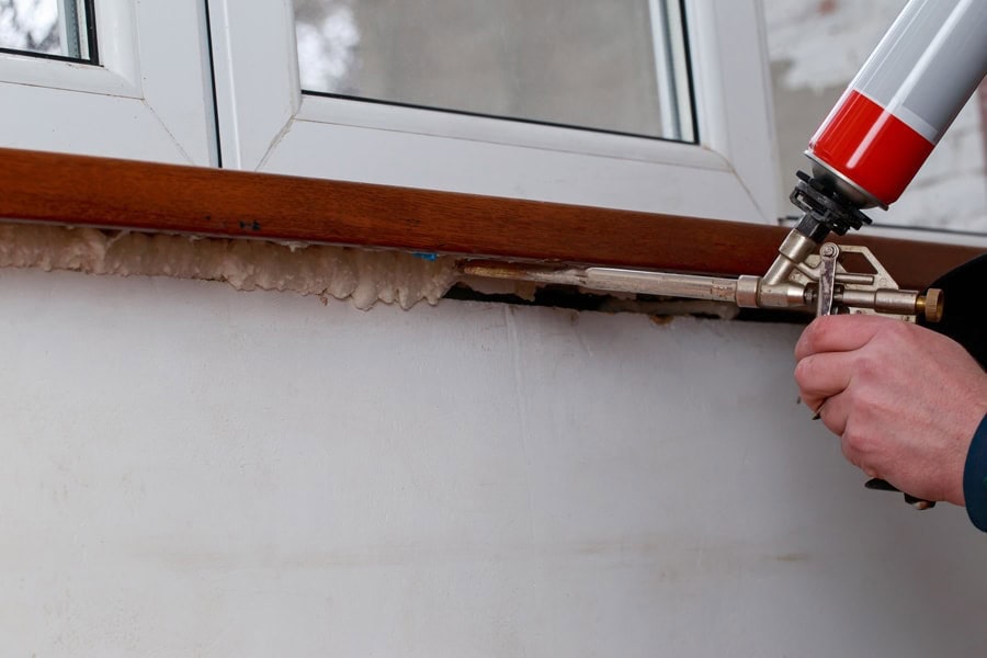 Common AC problems. Person using polyurethane foam in the installation of windows.