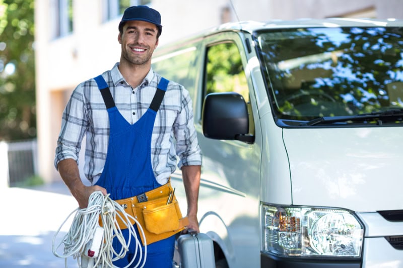 Portrait of happy carpenter with toolbox while standing by van.