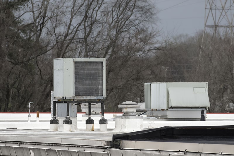 How Long Does a Commercial HVAC System Last? Horizontal shot of an old rooftop grocery air conditioning units in need of replacement.