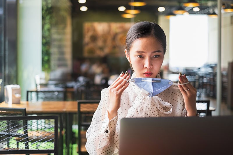 businesswoman wearing protective face mask while working with laptop.