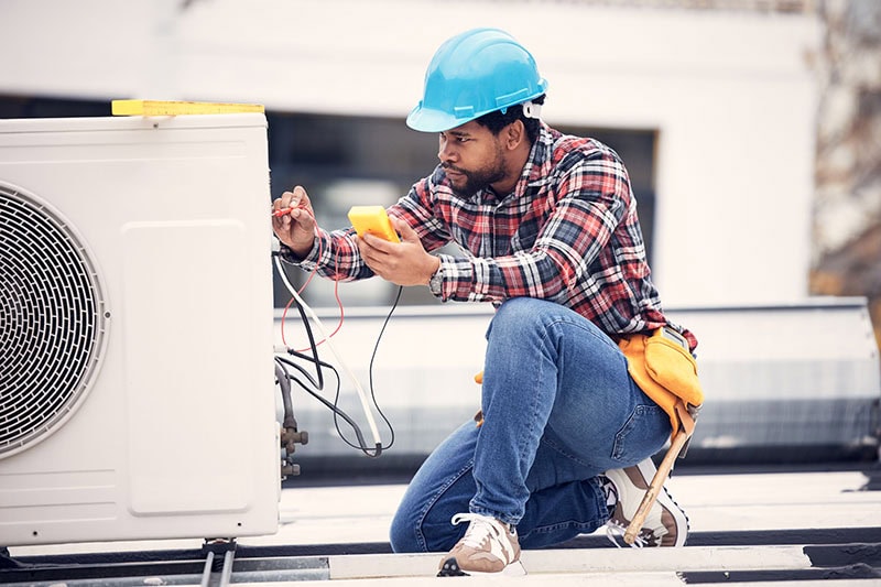 Air conditioner, cables and technician man ac repair, maintenance or working on electrical power generator. African person, electrician or contractor with electricity, heat pump check and engineering.
