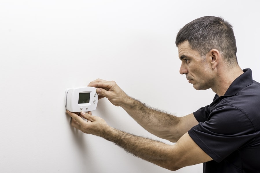 Hvac technician installing faceplate on a digital thermostat