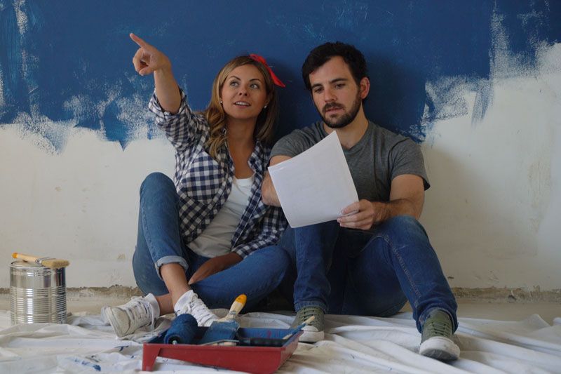 Image of a couple sitting down together after painting. Video - Remodeling Your Home? Don’t Forget Your Comfort!