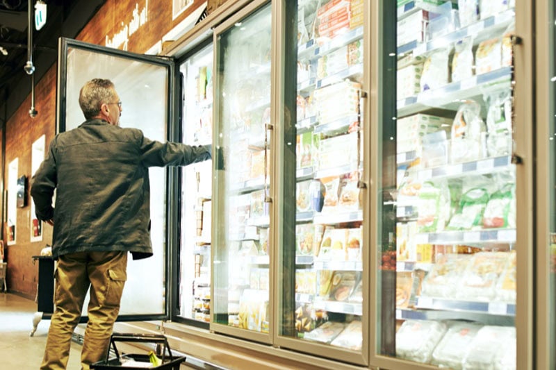 How to Maintain Your Commercial Food Refrigeration System. Photo of a man reaching into a commercial refrigerator.