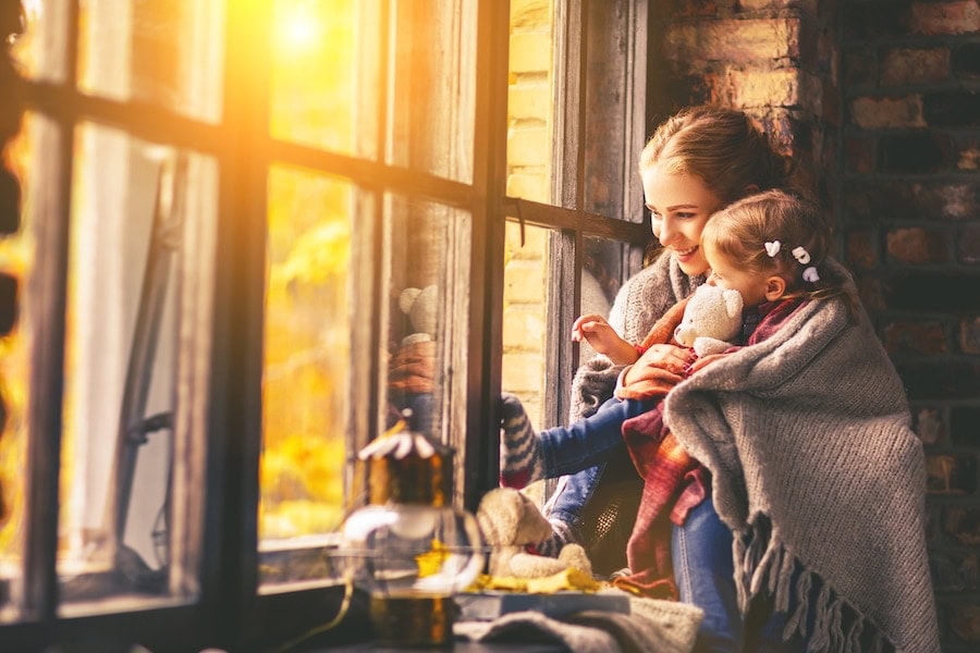 mother and daughter feeling cozy in blanket after following the 5 reasons to schedule a fall furnace clean and check