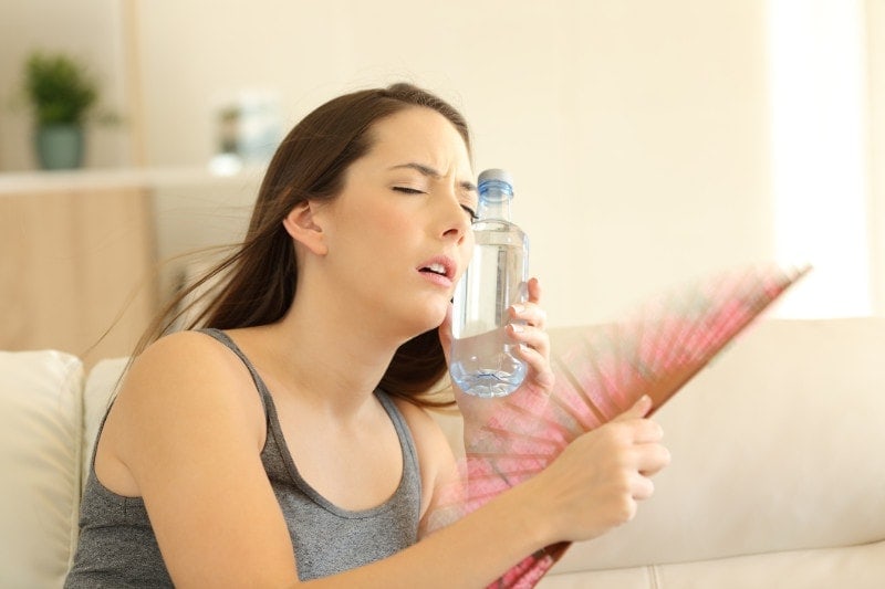 woman trying to stay cool due to broken ac unit in her home